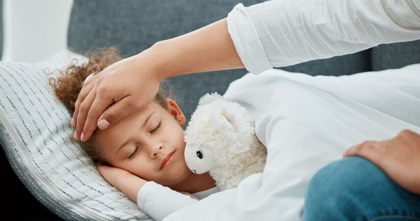 przeziębione dziecko śpi, a rodzic sprawdza temperaturę ciała, przeziębienie u dziecka, przeziębienie u dzieci, objawy przeziębienia u dzieci, czy przeziębione dziecko może wychodzić na dwór