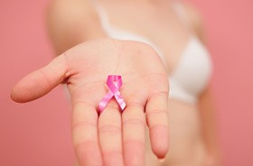 Różowa wstążka jako symbol raka piersi na wyciągniętej dłoni