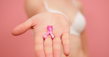 Różowa wstążka jako symbol raka piersi na wyciągniętej dłoni