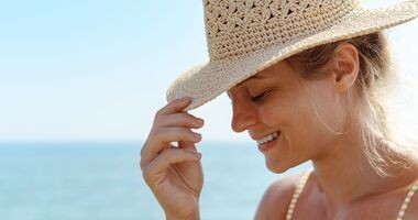 retinol latem, czy latem stosować retinol, kobieta w letnim kapeluszu na plaży