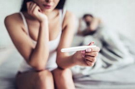 Kobieta z testem ciążowym w dłoni czeka na wynik badania. być może wskazuje to na problemy z płodnością