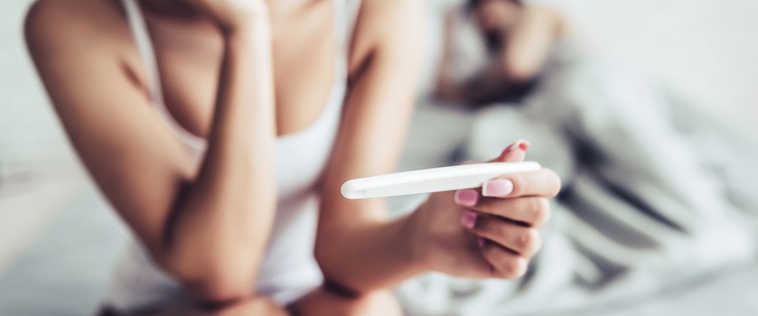 Kobieta z testem ciążowym w dłoni czeka na wynik badania. być może wskazuje to na problemy z płodnością