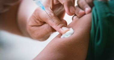 Podanie szczepionki na krztusiec. Ręka medyka dociskająca wacik na ramieniu zaszczepionego pacjenta. szczepienie krztusiec