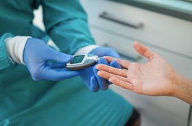 Lekarz bada poziom cukru we krwi u pacjenta chorego na COVID-19