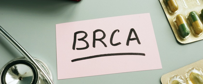 Napis BRCA na kawałku papieru, który leży na stole obok stetoskopu i tabletek