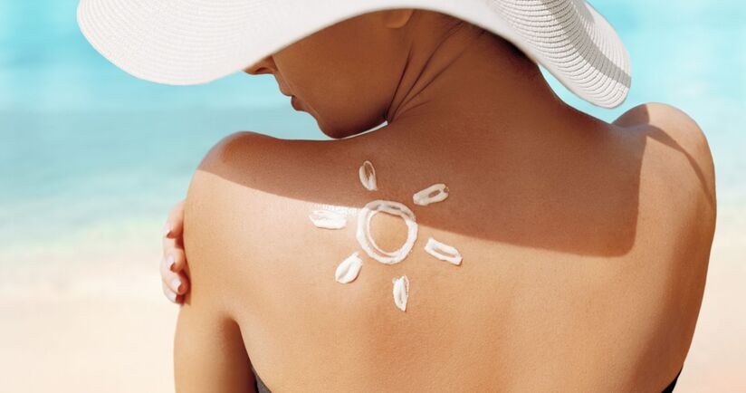 spf, wskaźnik spf, kobieta w kapeluszu na plaży wsmarowuje spf