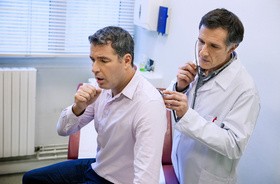 mężczyzna kaszle podczas badania stetoskopem