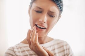 kobieta smaruje opryszczkę na ustach, opryszczka, co na opryszczkę