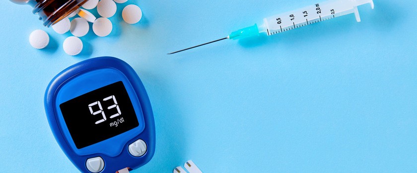 Tabletki, glukometr i paski do glukometru na cukrzycę leżą na niebieskim stole