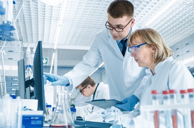 Dwóch naukowców dyskuje o wynikach badań klinicznych wyświetlonych na monitorze