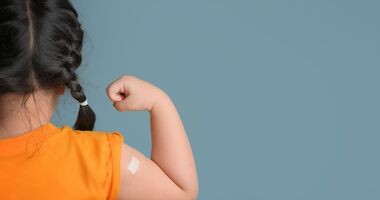 zaszczepionka dziewczynka, stoi tyłem i pokazuje plaster po szczepionce