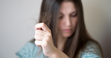 kobieta trzyma w dłoni wypadające włosy