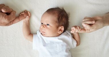 Noworodek trzyma za ręce rodziców. Wyprawka z apteki dla noworodka, wyprawka dla noworodka z apteki.