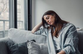 smutna kobieta z dystymią siedzi na kanapie, objawy dystymii, dystymia a depresja, czym jest dystymia