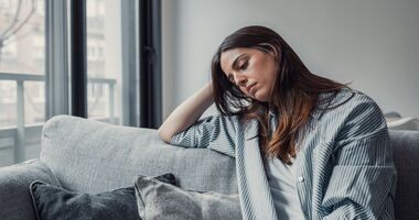 smutna kobieta z dystymią siedzi na kanapie, objawy dystymii, dystymia a depresja, czym jest dystymia