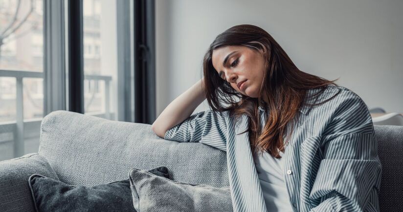 smutna kobieta z dystymią siedzi na kanapie, objawy dystymii, dystymia a depresja, czym jest dystymia