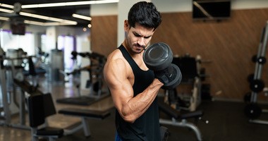 Mężczyzna ćwiczy na siłowni, prężąc biceps