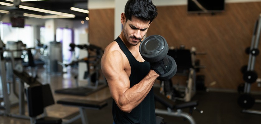Mężczyzna ćwiczy na siłowni, prężąc biceps