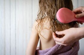 Rodzic rozczesuje dziecku włosy. Pielęgnacja włosów dziecka, jak dbać o włosy dziecka, jak myć włosy dziecku.