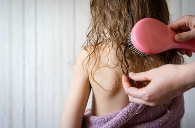 Rodzic rozczesuje dziecku włosy. Pielęgnacja włosów dziecka, jak dbać o włosy dziecka, jak myć włosy dziecku.