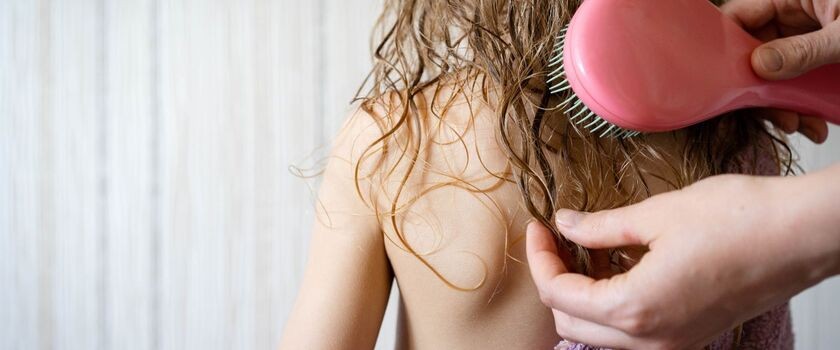 Rodzic rozczesuje dziecku włosy. Pielęgnacja włosów dziecka, jak dbać o włosy dziecka, jak myć włosy dziecku.