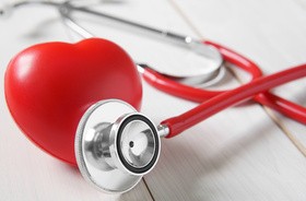 Zbliżenie na czerwone serce i stetoskop leżące na białym stole