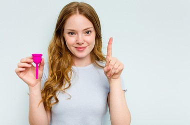 Młoda dziewczyna z kubeczkiem menstruacyjnym z radością i pewnością siebie wyczekuje swej pierwszej miesiączki