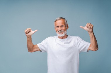 Starszy mężczyzna unosi ręce w geście zadowolenia