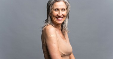 Uśmiechnięta starsza siwowłosa kobieta z plastrem medycznym po szczepieniu