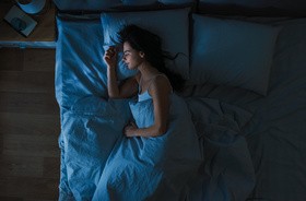 kobieta śpiąca w ciemnej sypialni