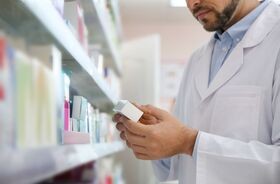 Farmaceuta przy półce w lekami. Refundacja leków od 1 stycznia 2026.