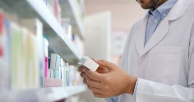 Farmaceuta przy półce w lekami. Refundacja leków od 1 stycznia 2026.