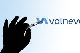 Strzykawka ze szczepionką przeciwko COVID-19 na tle logo firmy Valneva