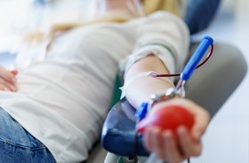 Młoda kobieta z zabawkowym sercem w dłoni oddaje krew