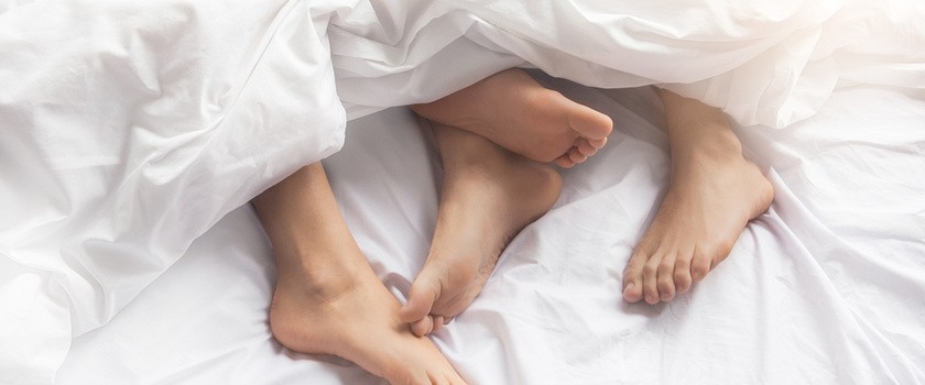 Nogi pary uprawiającej seks wystają spod kołdry