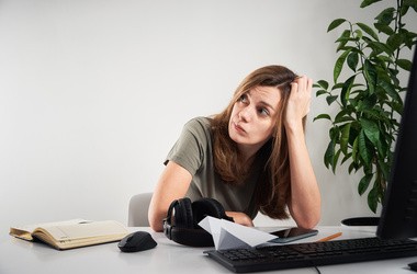 Zatroskana kobieta prokrastynuje w pracy, przy biurku