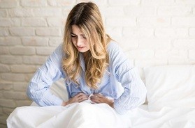 kobieta z bólami menstruacyjnymi trzyma się za brzuch
