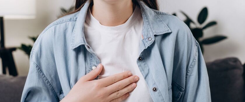 Kobieta trzymająca rękę na klatce piersiowej. Jaka dieta przy zgadze, zgaga, dieta na zgagę.