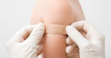 Ręce lekarza naklejające plaster po szczepieniu na ramię. NOP, niepożądany odczyn poszczepienny. 