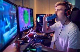 Chłopak grający na komputerze pije kolejnego energetyka