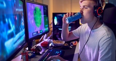 Chłopak grający na komputerze pije kolejnego energetyka
