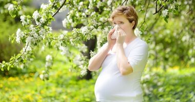 Kobieta w ciąży z alergią, objawiającą się katarem i kichaniem