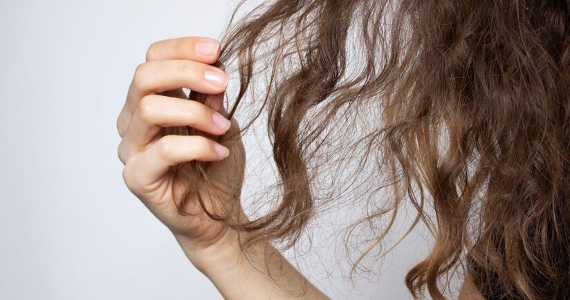 Kobieta przeczesuje dłonią włosy wysokoporowate.