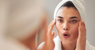 joga twarzy, joga na zmarszczki, jak ćwiczyć jogę twarzy, kobieta ćwiczy jogę twarzy w lustrze