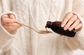 Kobieta trzymająca butelkę z syropem na kaszel