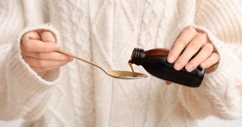 Kobieta trzymająca butelkę z syropem na kaszel