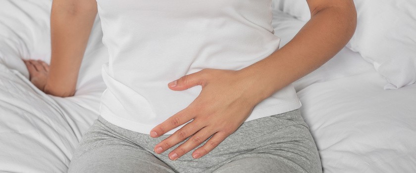 Zapalenie układu moczowego u kobiety siedzącej na łóżku i cierpiącej