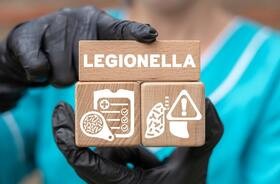 Napis legionella w formie drewnianych klocków wraz z symbolami, takimi jak objawy i leczenie legionelli