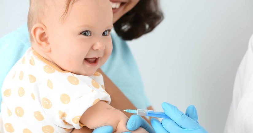 Dziecko na rękach matki przyjmuje szczepionkę przeciw pneumokokom. Szczepienie przeciw pneumokokom dla dzieci, szczepionka na pneumokoki dla dzieci.