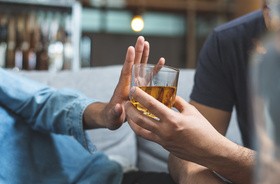 Mężczyzna odmawia picia alkoholu, blokując podawana mu szklankę dłonią